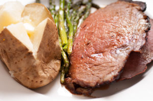 organic prime rib roast dinner with baked potato and asparagus